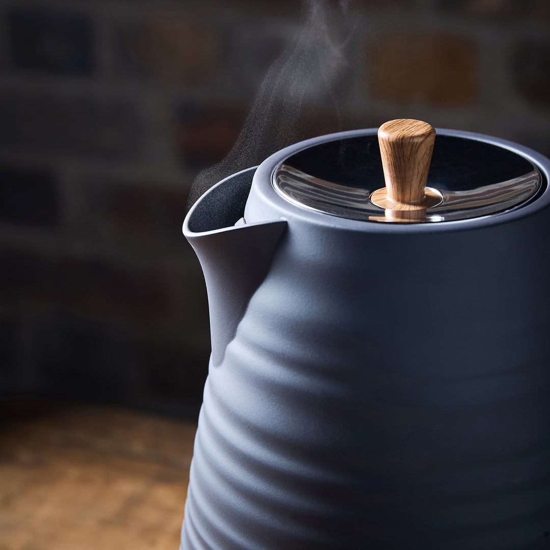 Blue Kettle with wooden handle and steam rising against a dark background