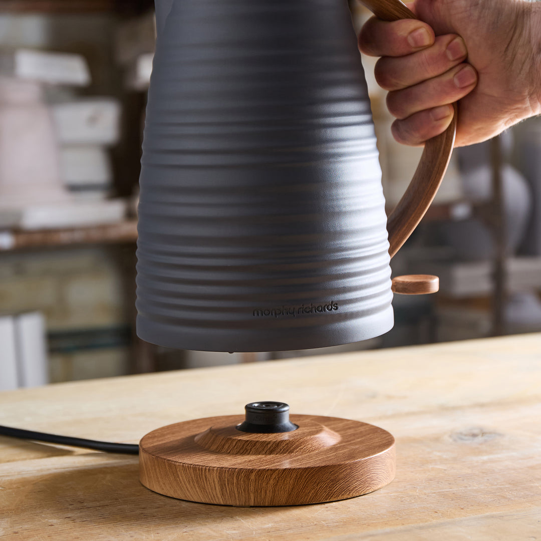 Ceramic kettle with wooden handle on a wooden surface, brand 'moooi' visible
