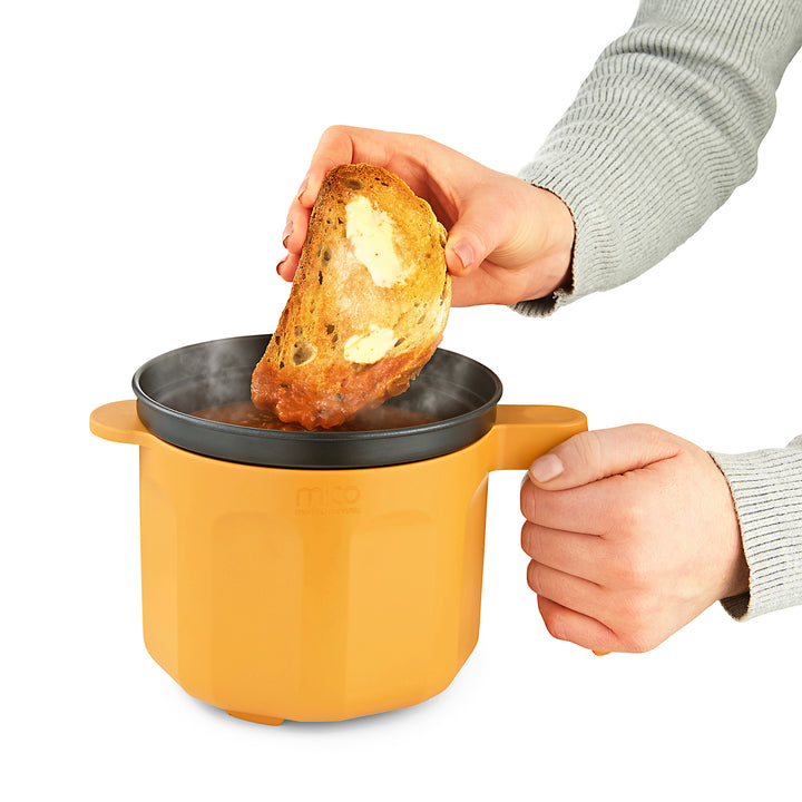 buttered toast being dunked into soup in the Microwave Saucepan