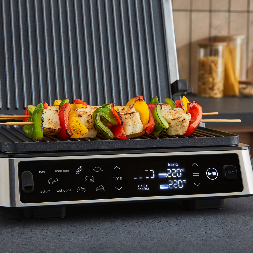 Portable grill with skewers of vegetables and meat on a kitchen counter