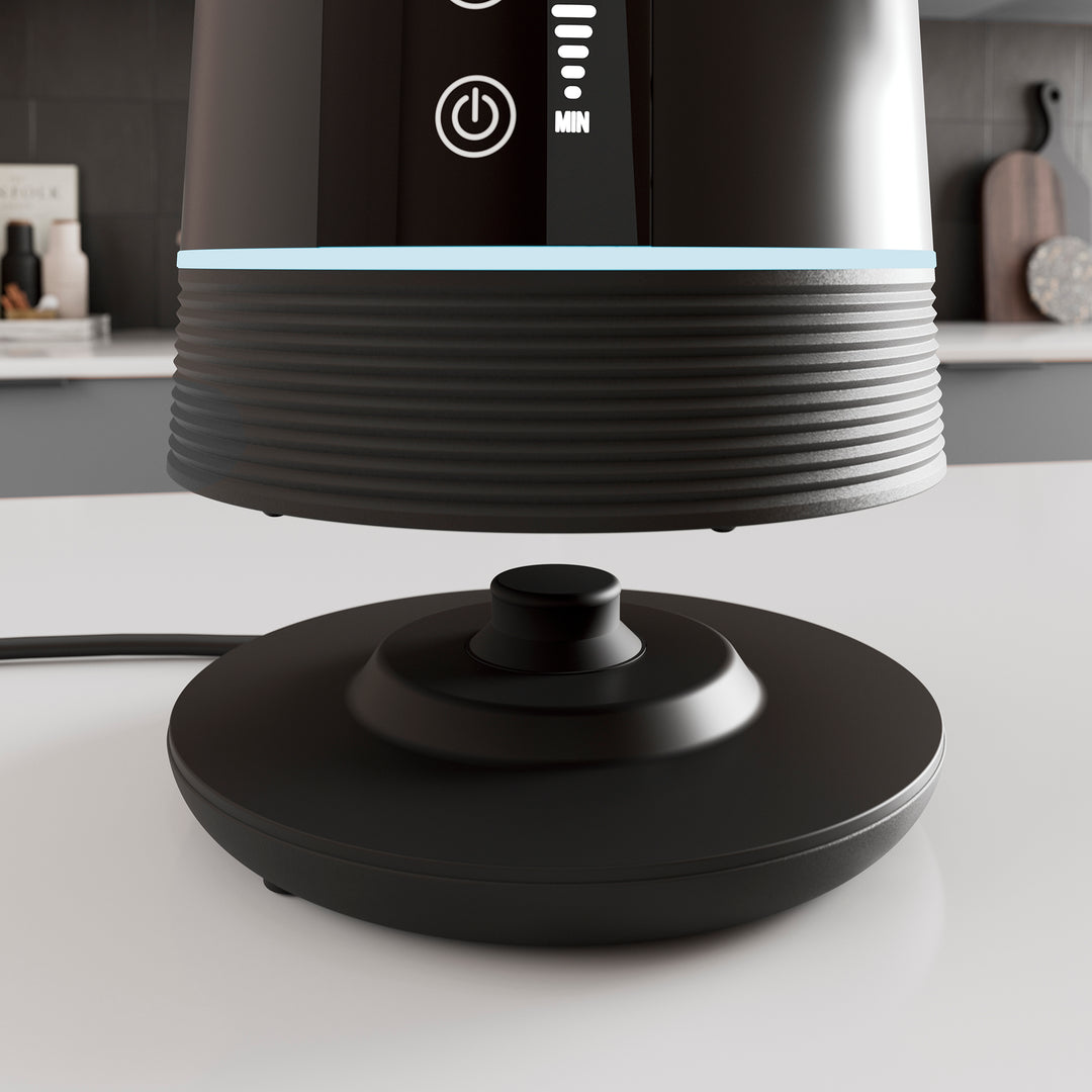 Black Alexa kettle base on a white surface with a blurred kitchen background