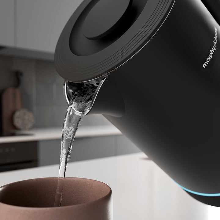 Black Alexa kettle pouring water into a brown mug on a kitchen counter.