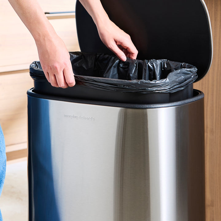 Someone taking the bin liner out to empty the bin