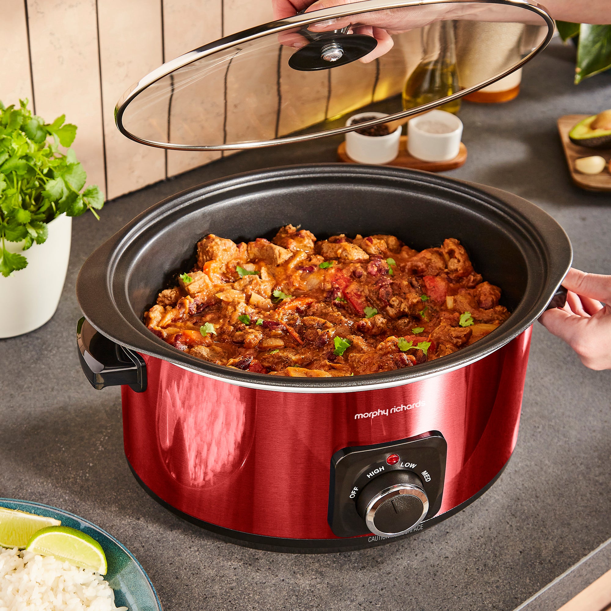 Red slow cooker with food inside on a kitchen counter