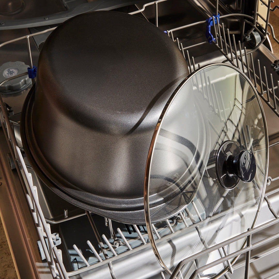 Dishwasher with dishes including a black pot and a glass lid.