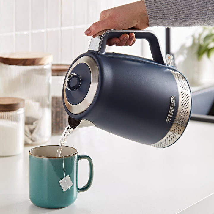 someone pouring biled water from blue kettle into a mug