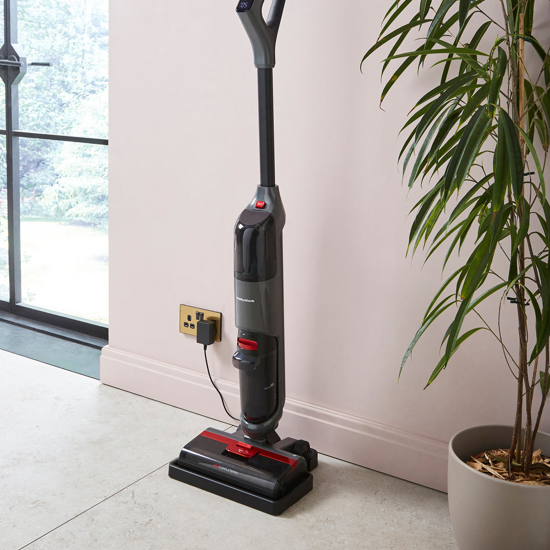 Black and red Morphy Richards floor cleaner in its stand on a tiled floor