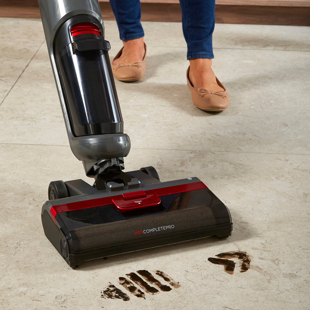 Person using a Morphy Richards floor cleaner on a tiled floor with visible dirt being picked up.