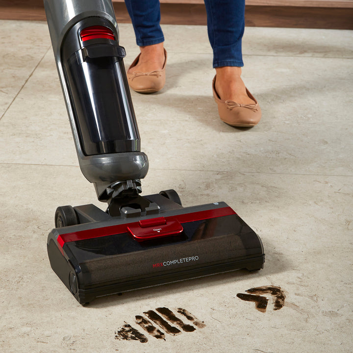Person using a Morphy Richards floor cleaner on a tiled floor with visible dirt being picked up.