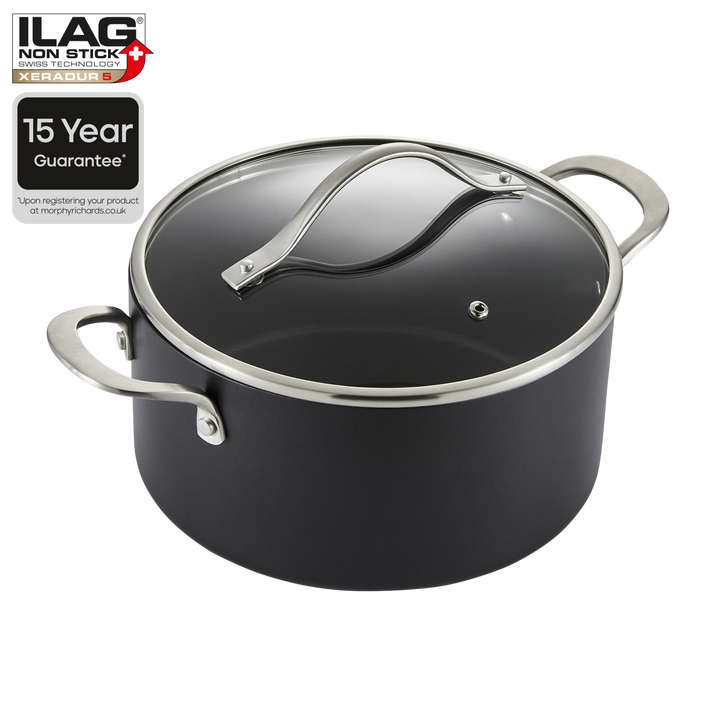 A black non-stick saucepan with a clear glass lid and silver metal handles, shown on a white background with an ILAG Non-Stick 15 Year Guarantee badge in the top-left corner.