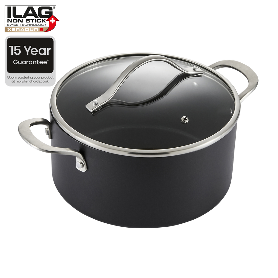 A black non-stick saucepan with a clear glass lid and silver metal handles, shown on a white background with an ILAG Non-Stick 15 Year Guarantee badge in the top-left corner.