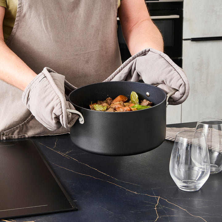 24cm Aluminium Non-Stick Casserole Dish on a granite countertop being held with its handles 