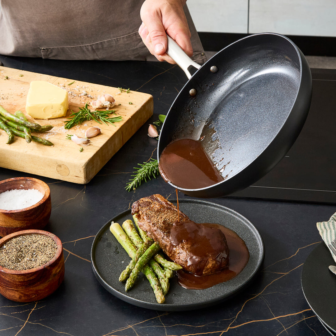 Tipping the sauce from the 26cm frying pan onto the steak 