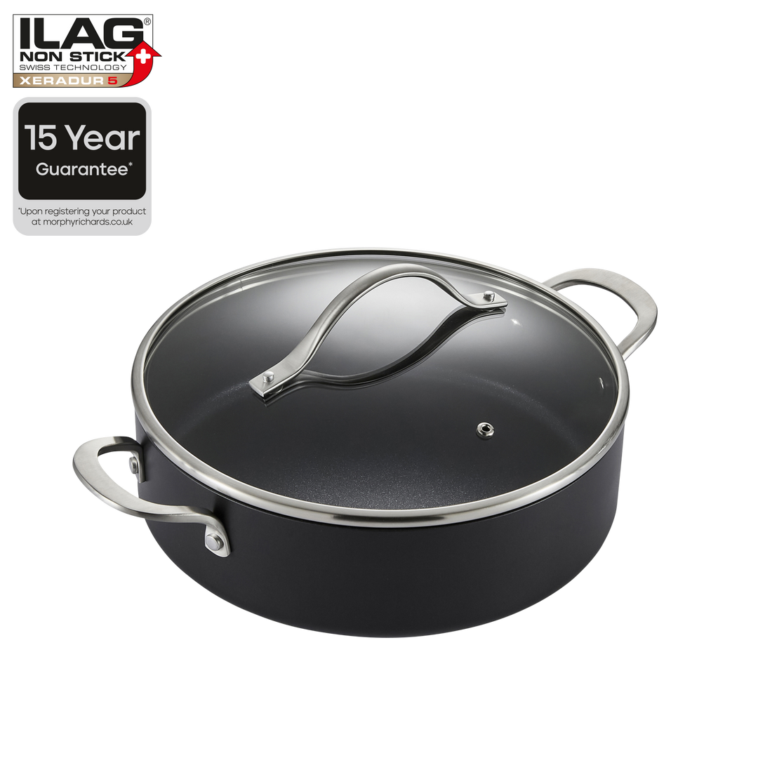 A black non-stick saucepan with a matching glass lid and silver metal handles, shown on a white background with ILAG brand badges and a 15-year guarantee graphic.