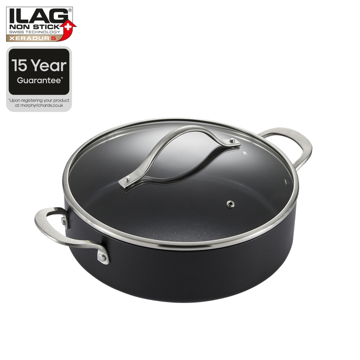 A black non-stick saucepan with a matching glass lid and silver metal handles, shown on a white background with ILAG brand badges and a 15-year guarantee graphic.