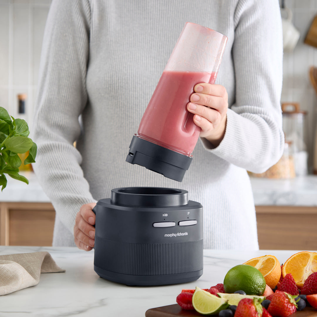 person adding the blender cup onto the base of a cordless blender 