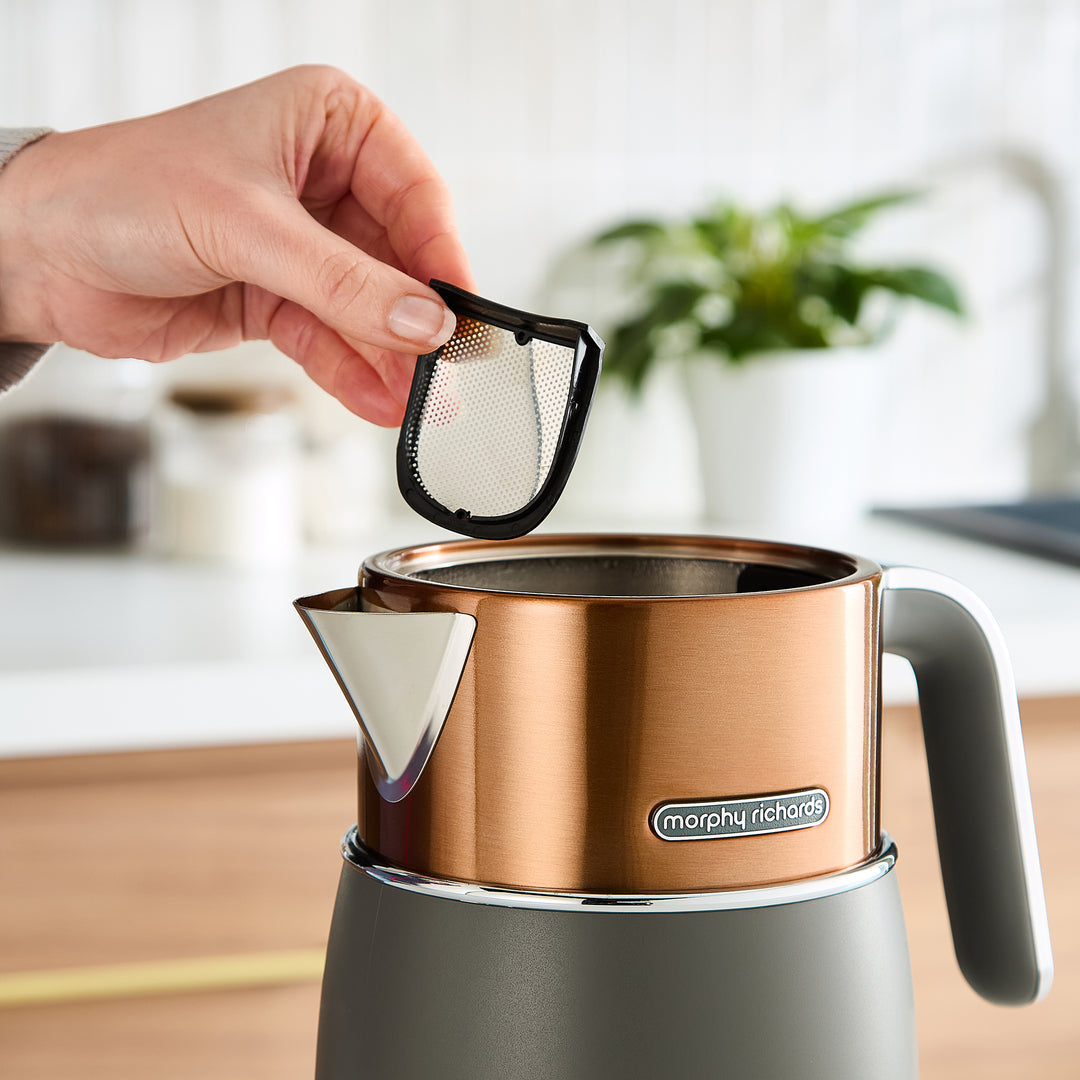 Person removing the filter from a copper and grey kettle