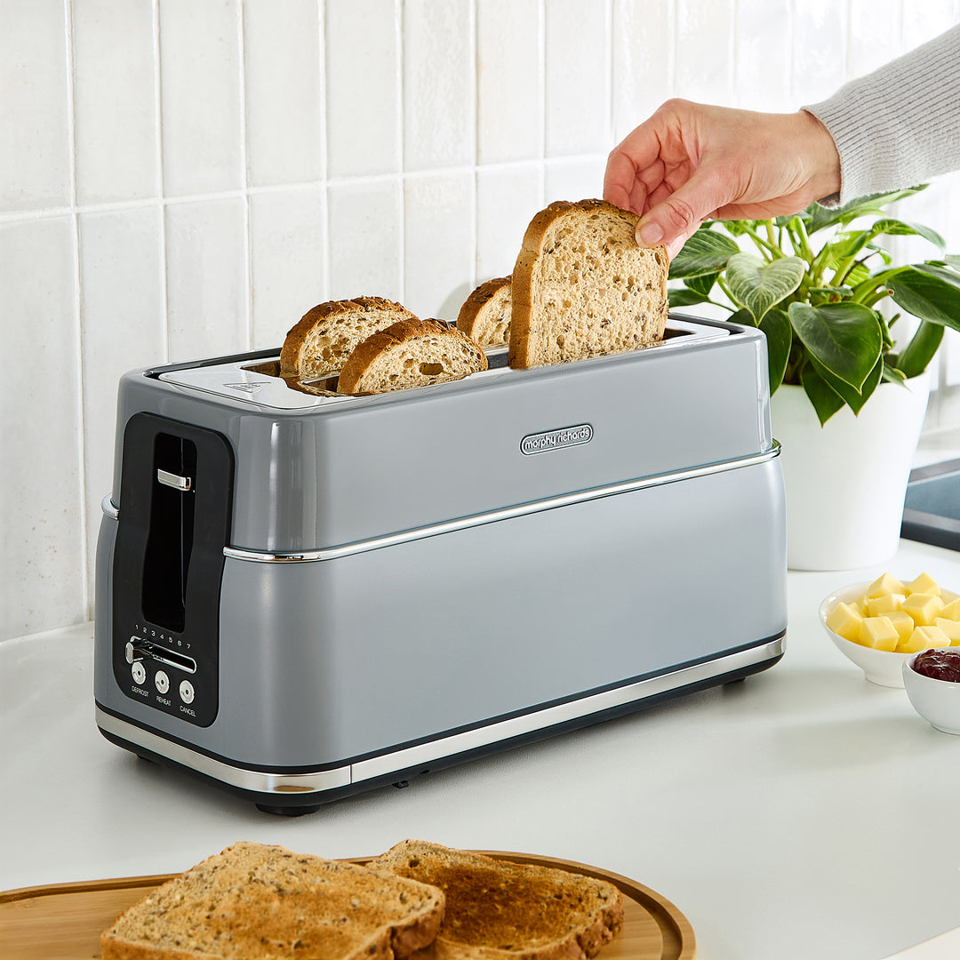 Person placing bread into a grey toaster 
