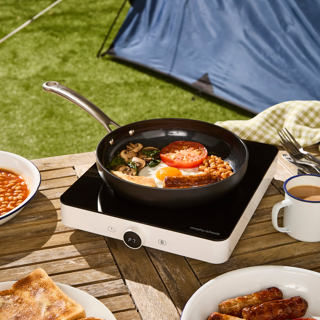 single induction hob outdoors with saucepan full of english breakfast on top