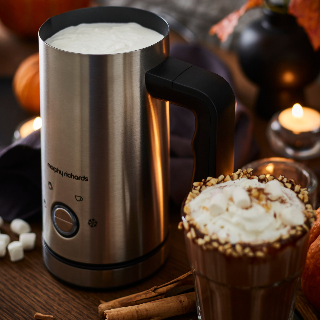 Electric milk frother with whipped cream and a cup of hot chocolate 